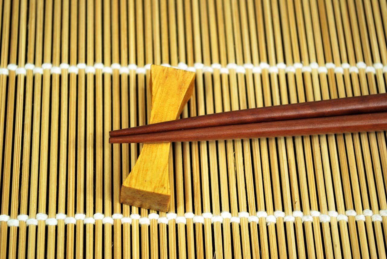 When placing your chopsticks down, you should use a chopstick rest. If you are using disposable chopsticks, you can fold up the paper container it come with and rest your chopstick on that. Photo source: julenka