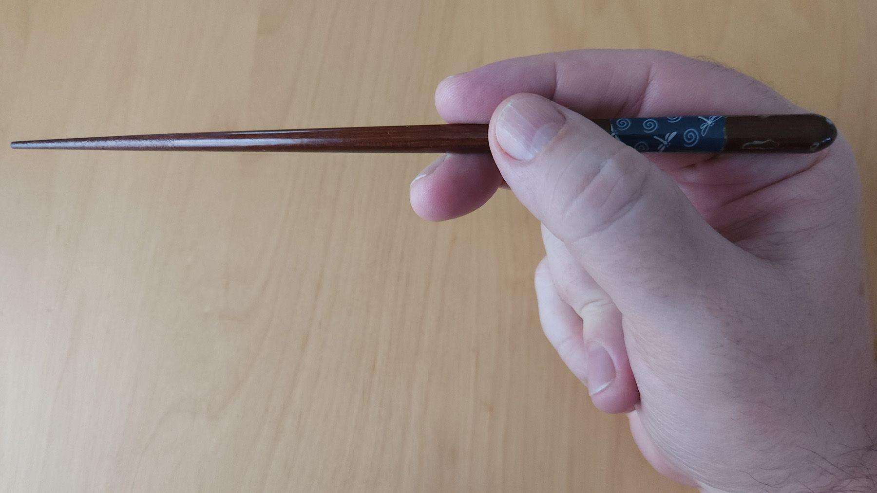 The top chopstick is held like a pencil. This top chopstick is the stick that moves up and down. Photo source: James Saunders-Wyndham