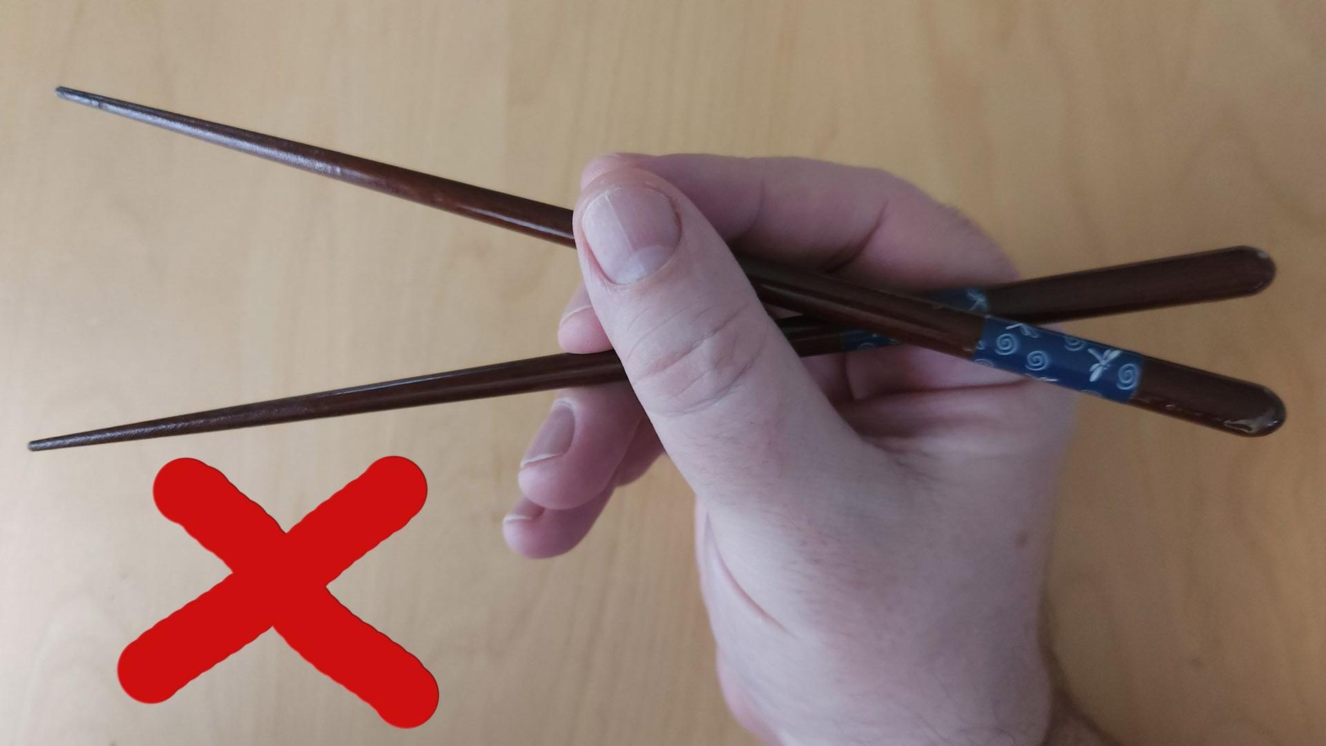 If you want to impress people with your chopstick skills, do NOT hold them in the middle and do NOT cross the sticks. Photo source: James Saunders-Wyndham